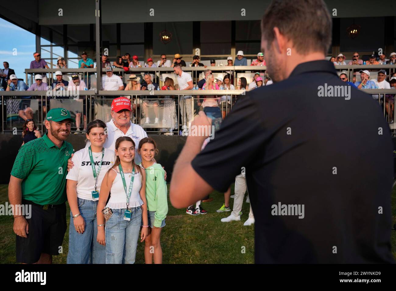 Eric Trump, right, takes a cell phone picture of Republican presidential candidate former President Donald Trump posing with golfer Louis Oosthuizen, left, and members of his family, at the end of the final round of LIV Golf Miami, at Trump National Doral Golf Club, Sunday, April 7, 2024, in Doral, Fla. (AP Photo/Rebecca Blackwell) Banque D'Images