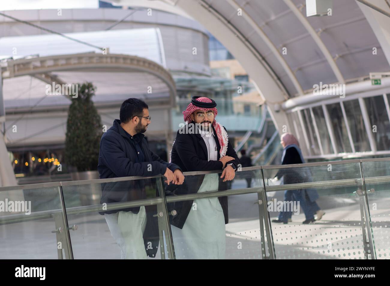 Deux hommes arabes parlent les uns aux autres dans un endroit moderne à l'extérieur comme un magasin de centre commercial et d'immenses aires de jeux sur la vie professionnelle et les problèmes Banque D'Images