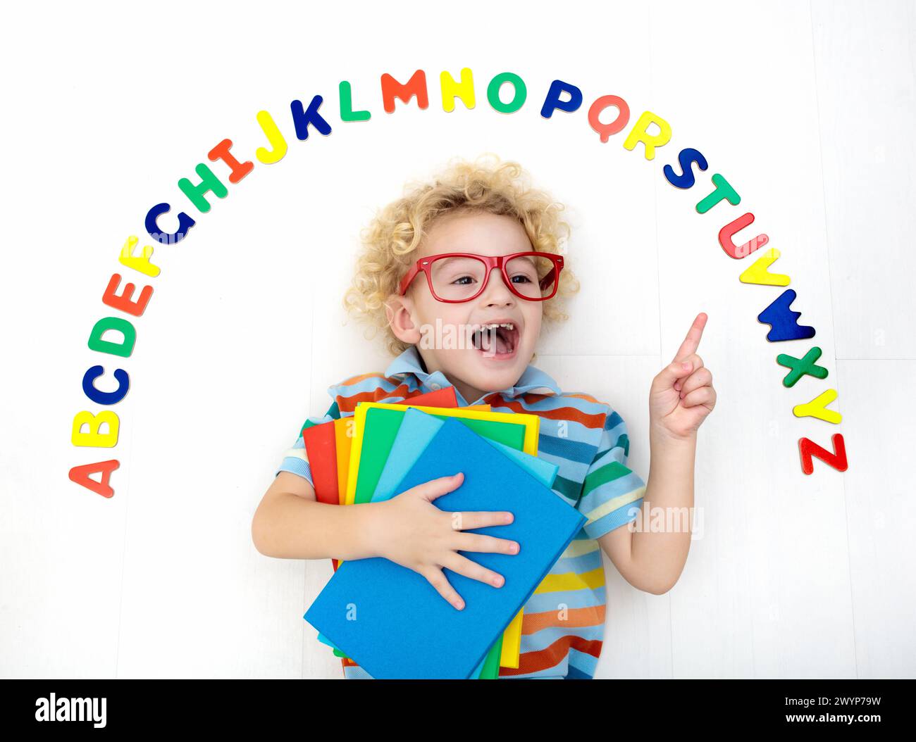Heureux l'enfant d'âge préscolaire d'apprendre à lire et à écrire en jouant avec les lettres de l'alphabet romain coloré. Abc de l'éducation des jouets et livres pour enfants. Élève de l'école Banque D'Images