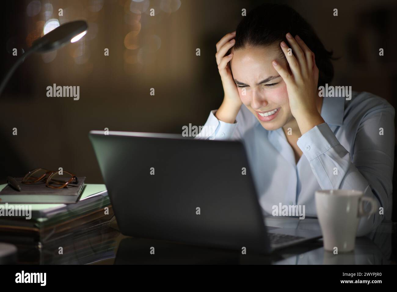 Femme d'affaires désespérée vérifiant l'ordinateur portable dans la nuit au bureau à domicile Banque D'Images