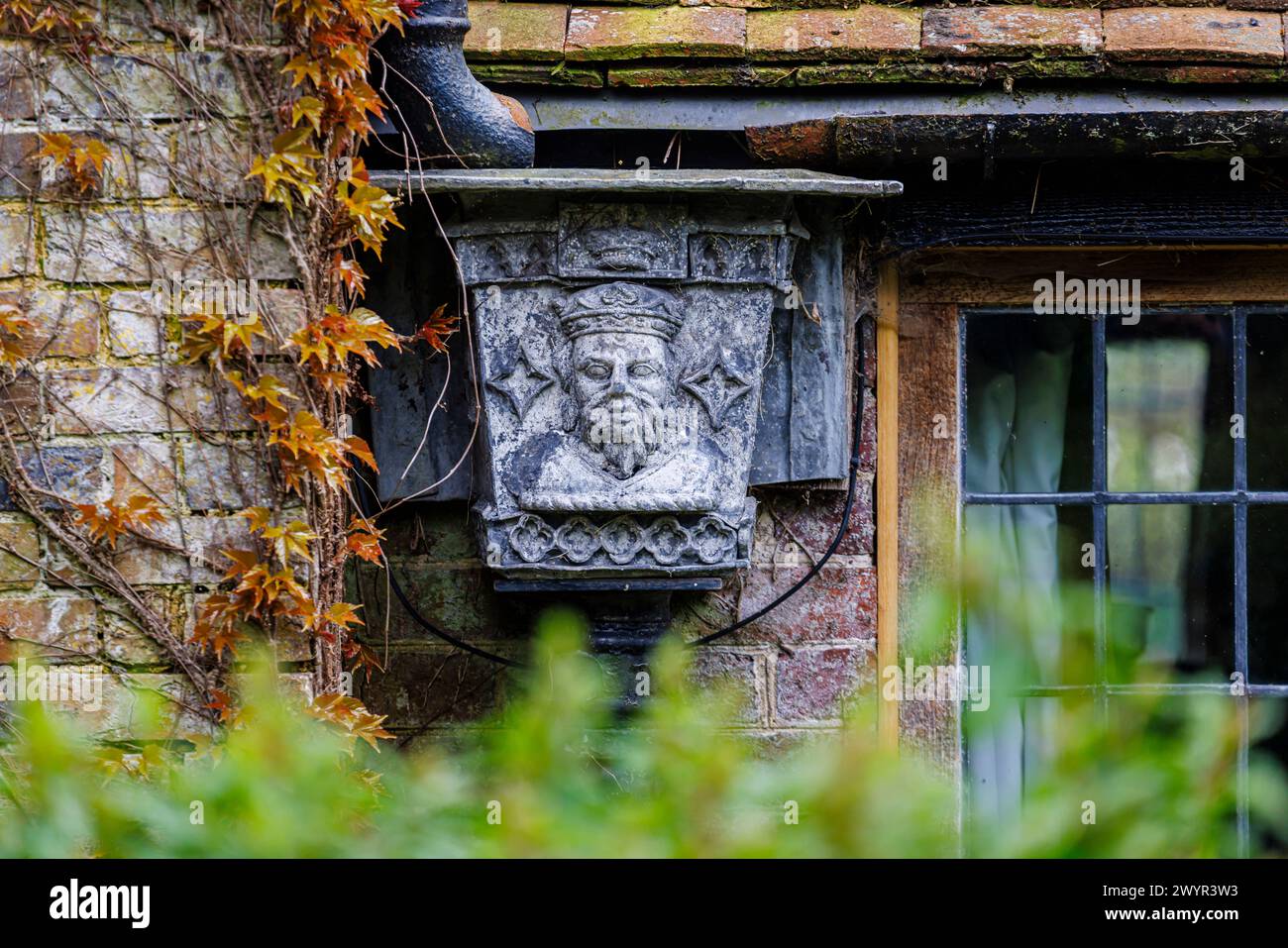 Une trémie en métal vintage avec le portrait d'un roi couronné dans le système de gouttières de Vann House près de Hambledon, Surrey au début du printemps Banque D'Images