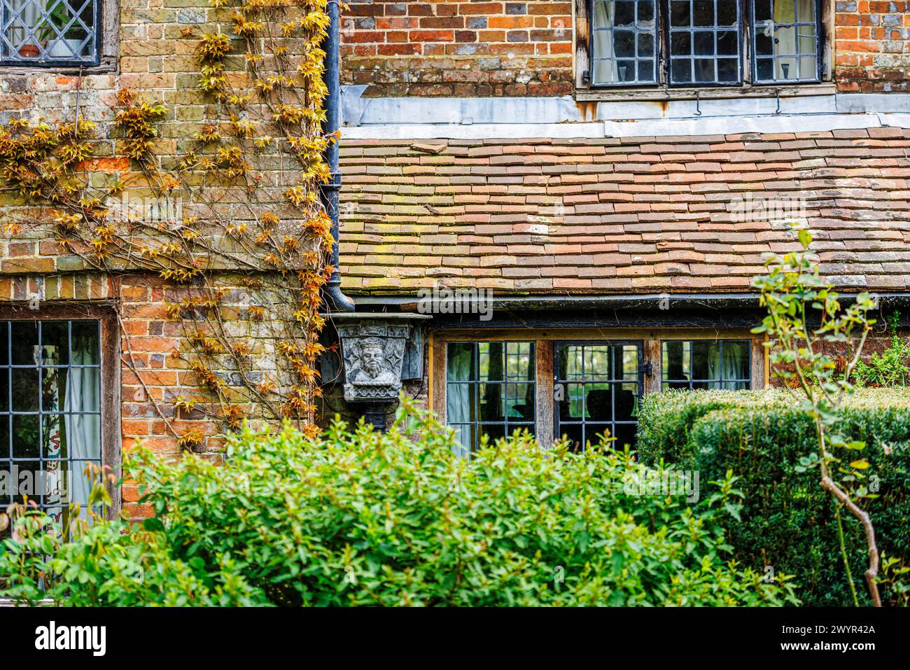 Une trémie en métal vintage avec le portrait d'un roi couronné dans le système de gouttières de Vann House près de Hambledon, Surrey au début du printemps Banque D'Images