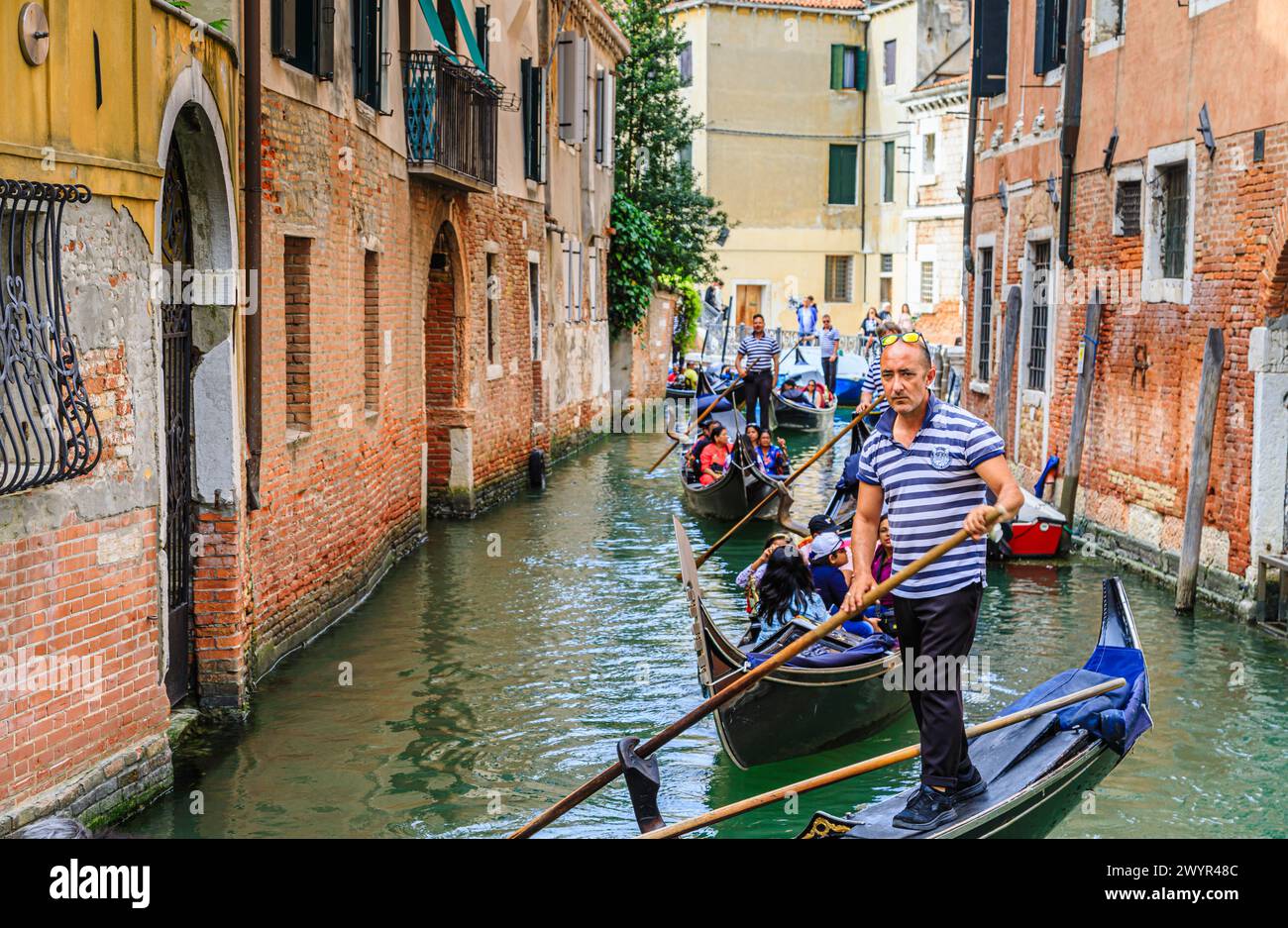 Excursions touristiques traditionnelles en bateau : promenades en gondole sur des gondoles typiques avec des gondoles sur un canal étroit animé dans la région du Castello de Venise, en Italie Banque D'Images