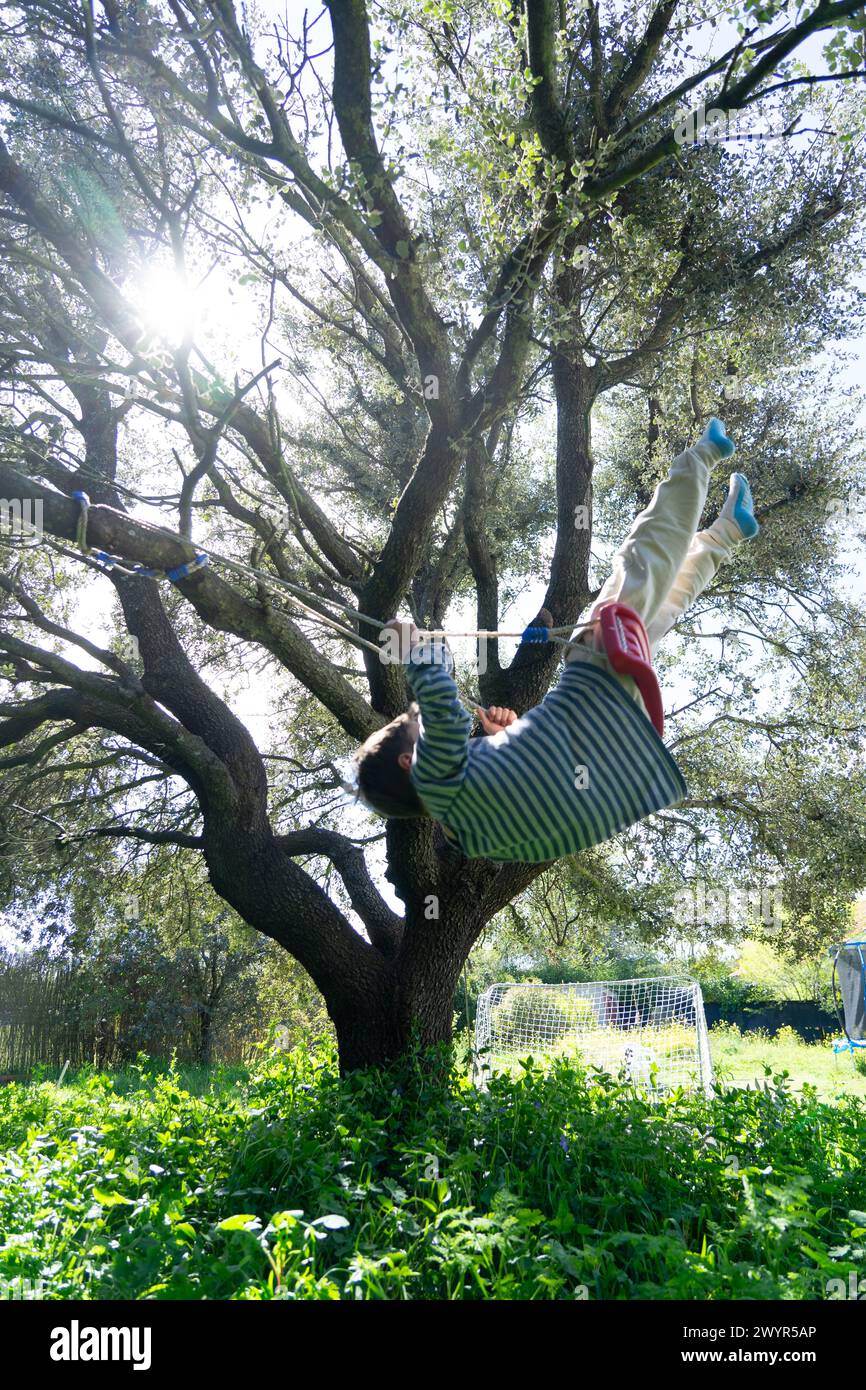 Enfant se balançant sur une balançoire suspendue à un arbre Banque D'Images