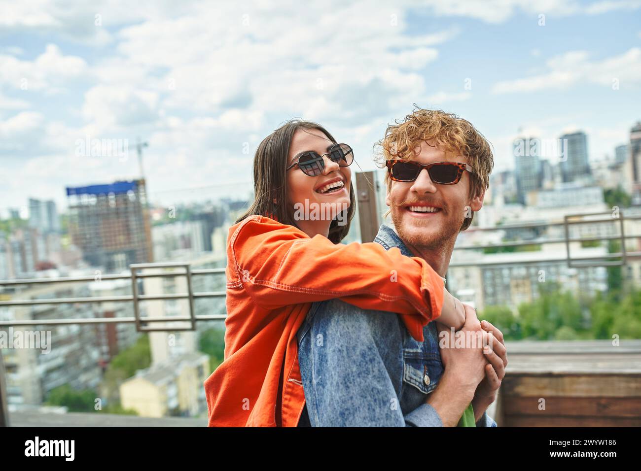 Un homme tenant une femme pendant qu'ils dansent sur un toit, sur un fond de ville Banque D'Images
