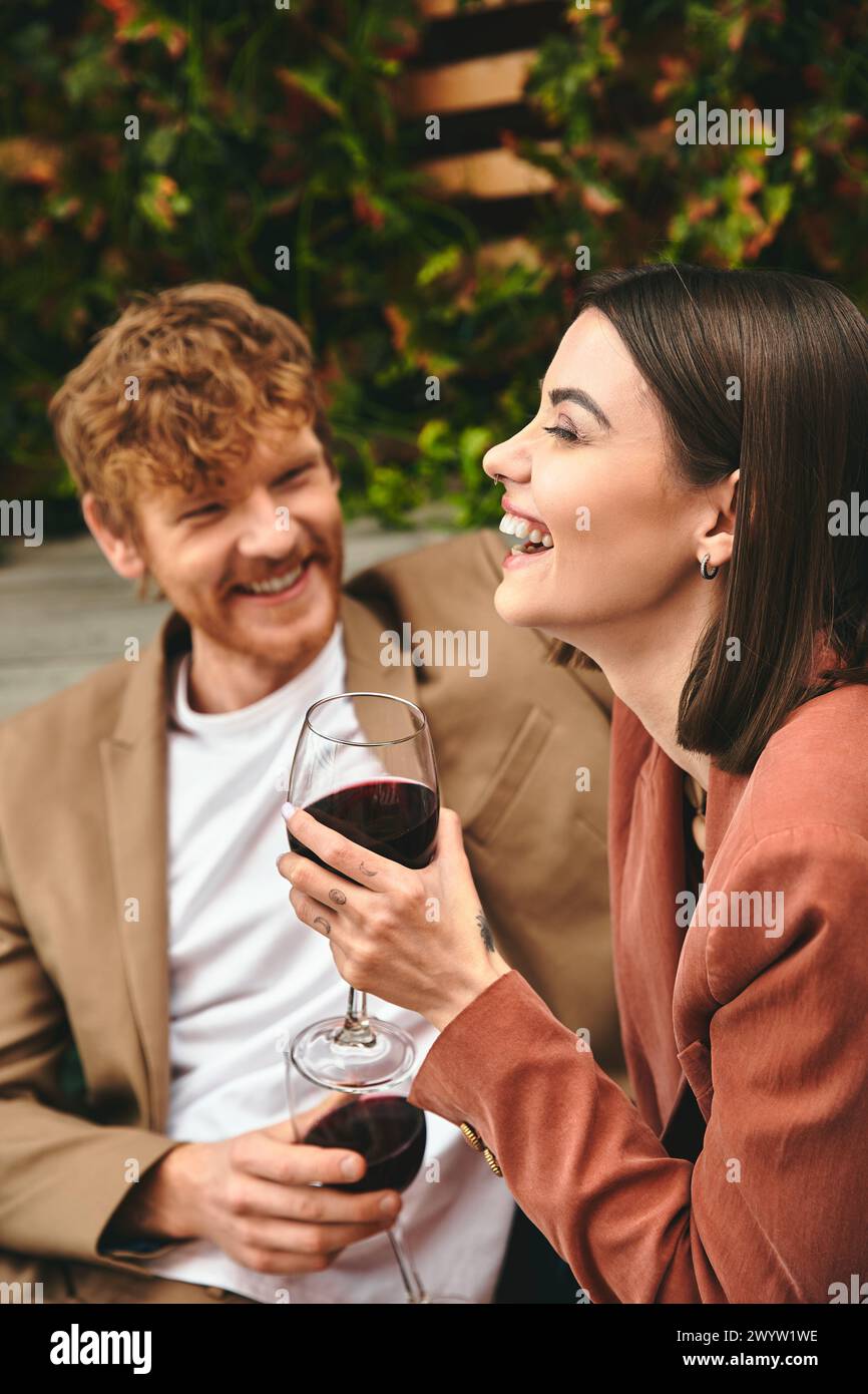 Un homme et une femme sont assis côte à côte, serrant des verres à vin dans un geste romantique Banque D'Images