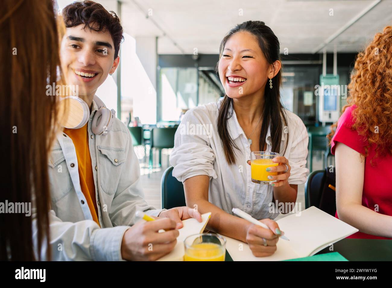 Heureux jeune groupe diversifié d'étudiants assis ensemble au collège du campus. Banque D'Images