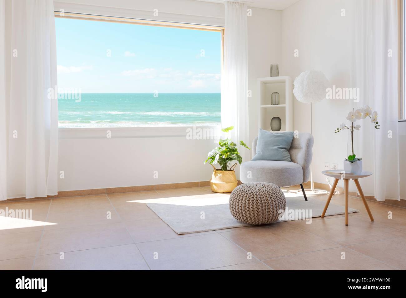 Détail d'appartement ou salon avec vue sur la mer par une journée ensoleillée. Espace romantique avec grande fenêtre et fauteuil et tapis sur la gauche. Il y a un sentiment Banque D'Images