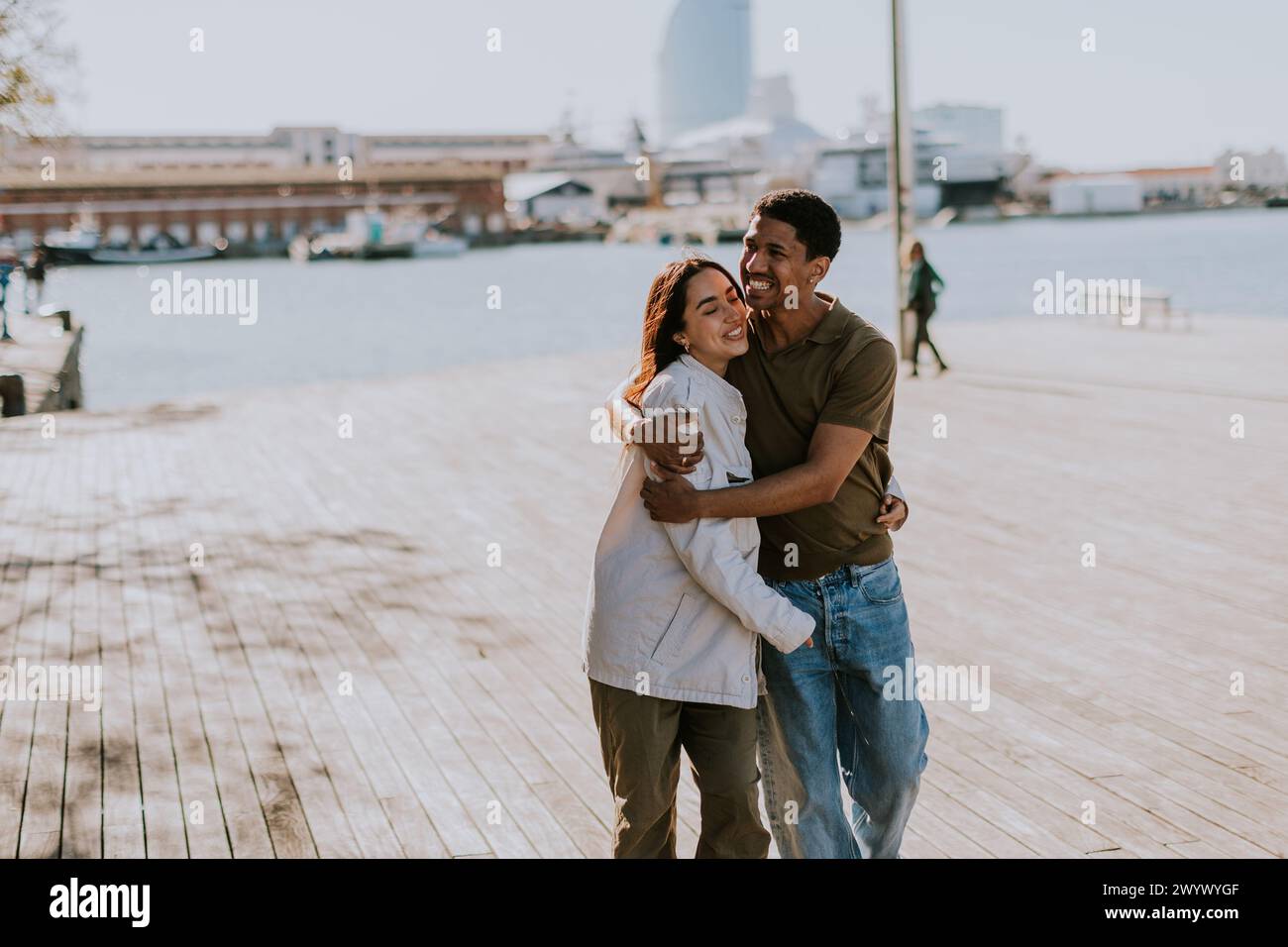 Joyeux couple embrasse sur un quai à Barcelone, avec l'horizon de la ville légèrement flou en arrière-plan Banque D'Images