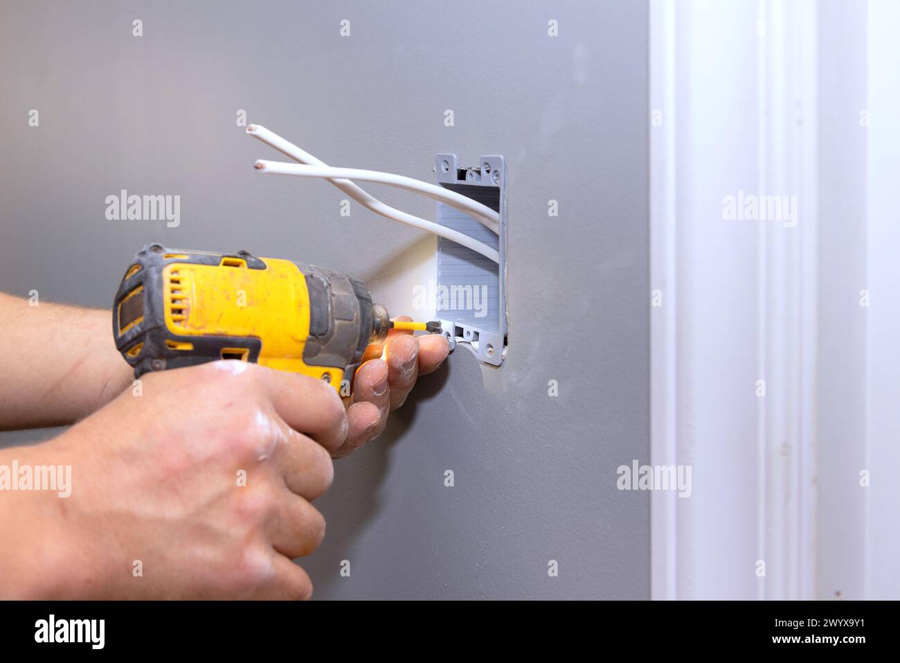 En cours de rénovation de résidence, un électricien professionnel connecte une prise électrique au mur Banque D'Images