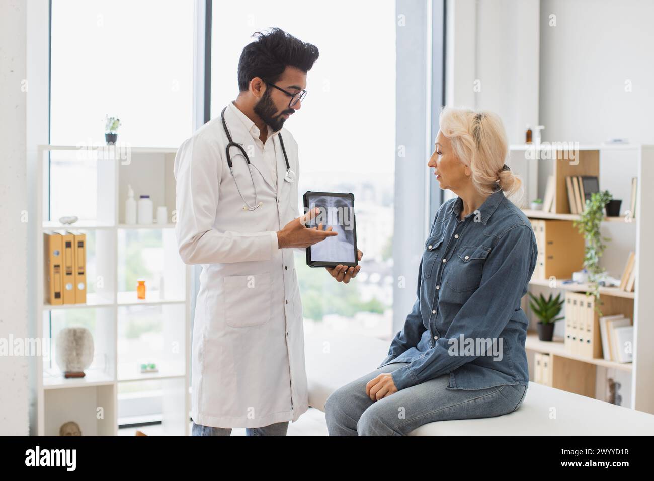 Homme barbu en blouse de laboratoire tenant un comprimé avec IRM. Banque D'Images