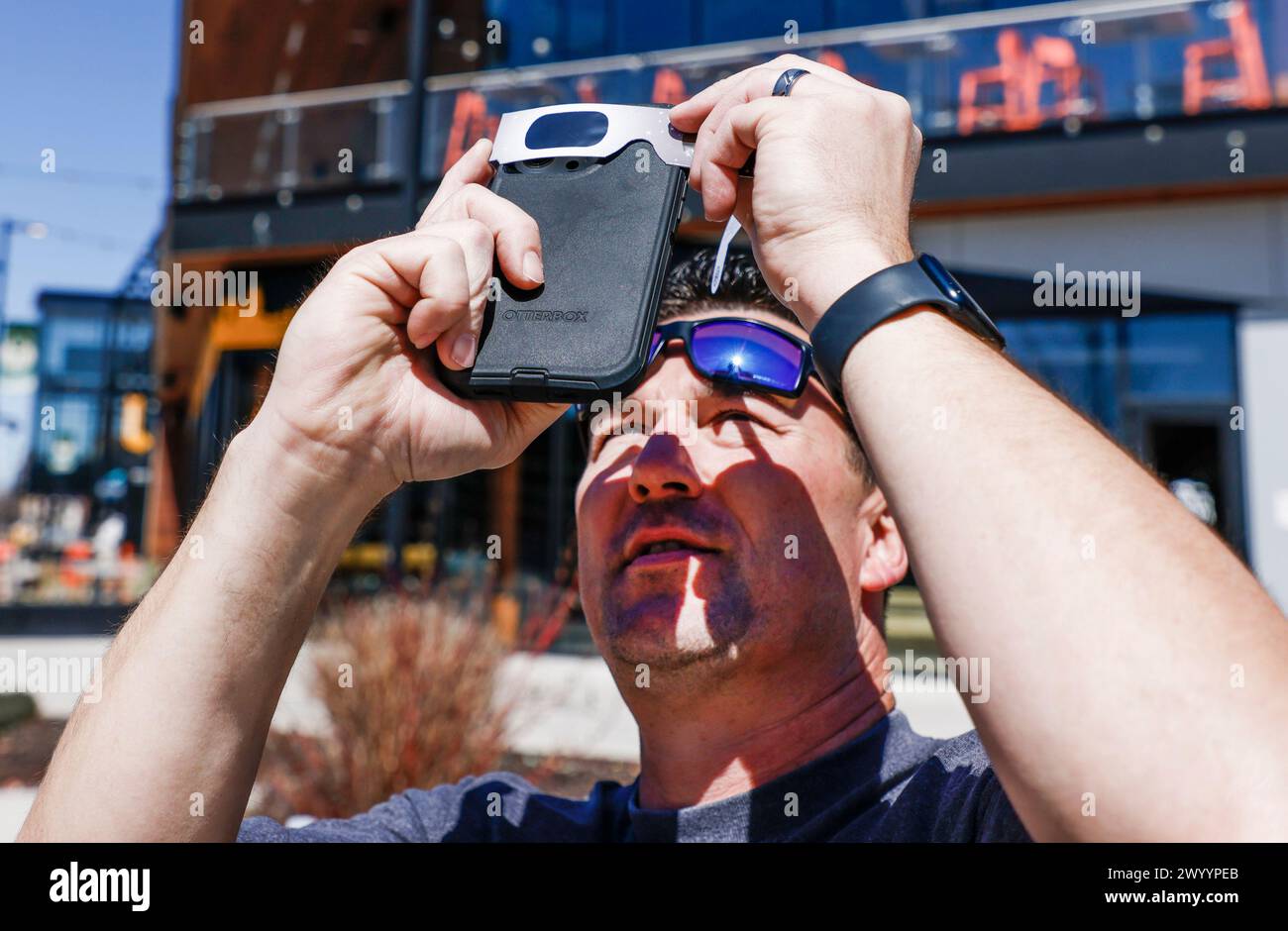 Milwaukee, États-Unis. 08 avril 2024. Jonathan Moore utilise des lunettes solaires alors qu'il essaie de prendre une photo avec son téléphone portable alors que la lune se déplace sur le soleil pendant l'éclipse solaire de 2024 à Milwaukee, Wisconsin, le lundi 8 avril 2024. La dernière éclipse en Amérique du Nord remonte à 2017 et la prochaine sera en 2044. Photo de Tannen Maury/UPI crédit : UPI/Alamy Live News Banque D'Images