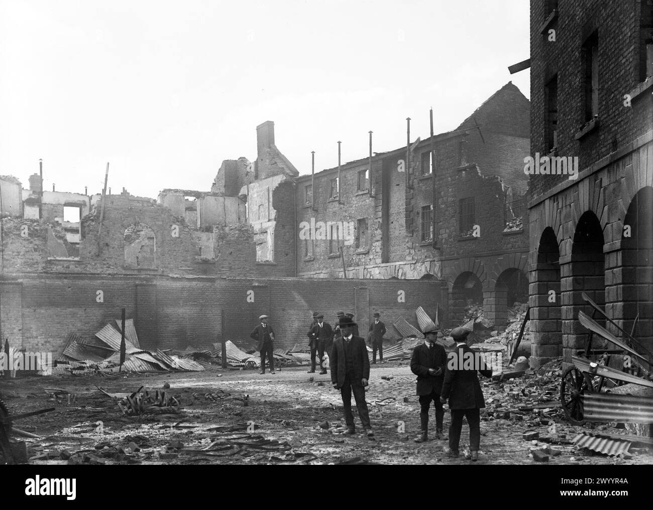 Photographie vintage. Dublin, Irlande mai 1916. Dommages aux rues à la suite du soulèvement de Pâques à Dublin. Hommes inspectant l'épave de Linenhall Barracks Banque D'Images