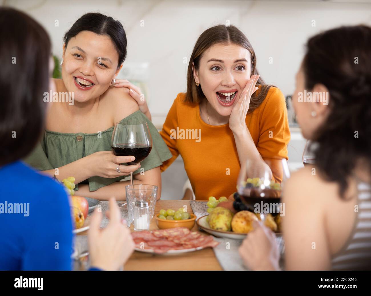 Des femmes heureuses se sont rassemblées autour d’une table festive, participant à des discussions animées et profitant des délices du vin Banque D'Images