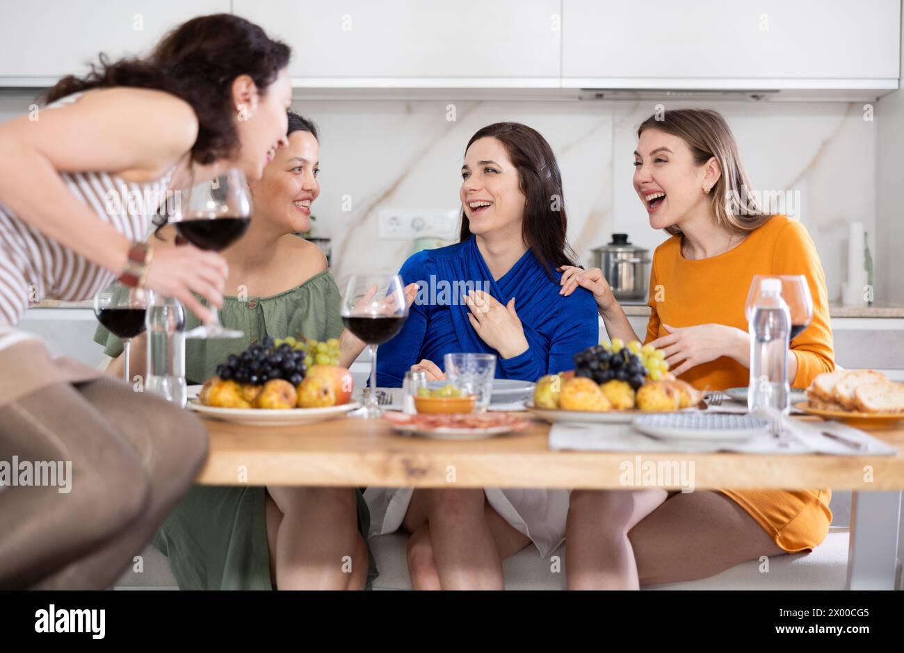 Des femmes heureuses se sont rassemblées autour d’une table festive, participant à des discussions animées et profitant des délices du vin Banque D'Images