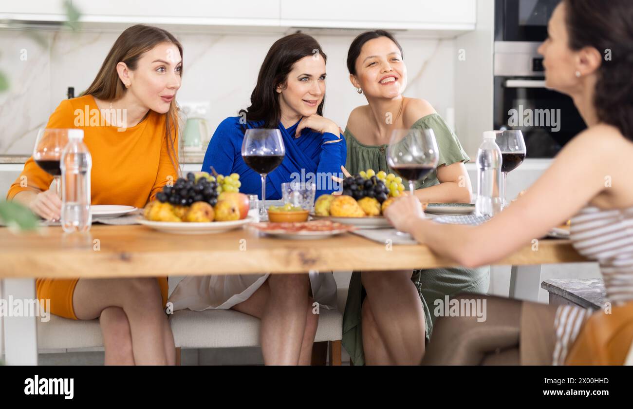Des femmes heureuses se sont rassemblées autour d’une table festive, participant à des discussions animées et profitant des délices du vin Banque D'Images