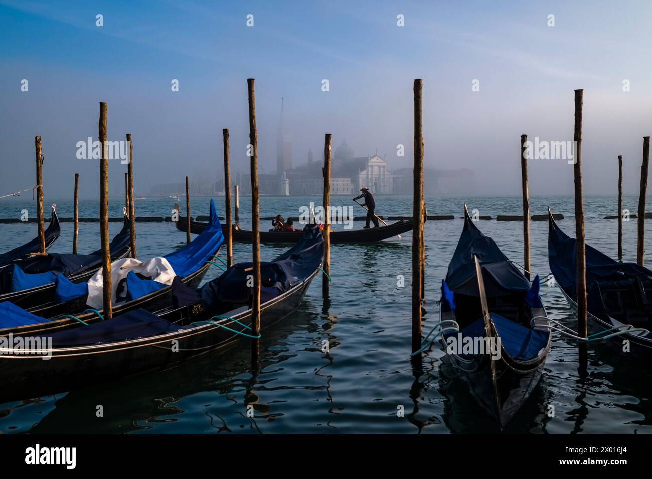 Les gondoles, les bateaux à rames vénitiens traditionnels, sont attachés au Canale della Giudecca, île et église San Giorgio di Maggiore, entourés de brume Banque D'Images