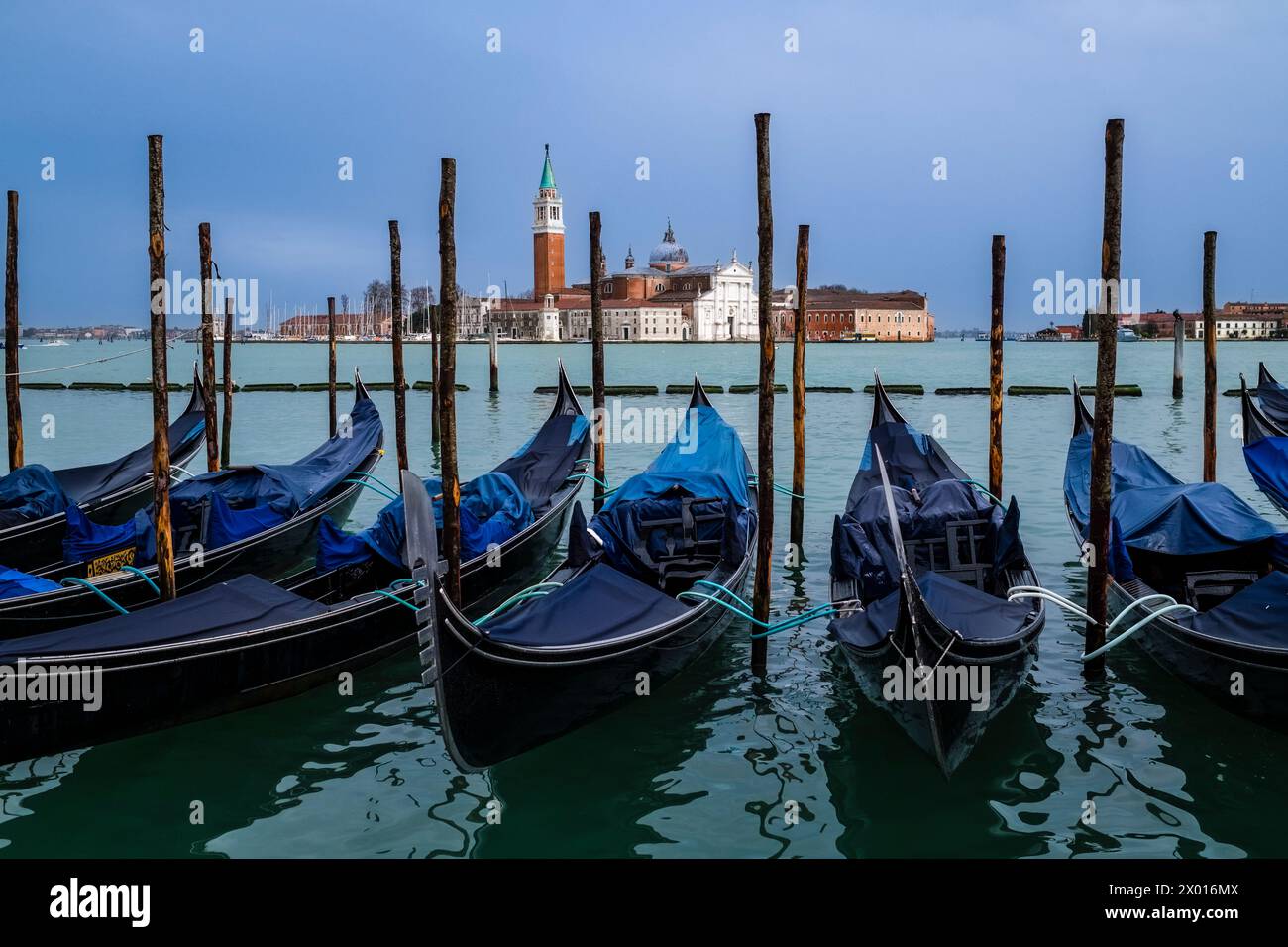 Les gondoles, les bateaux à rames vénitiens traditionnels, sont attachés au Canale della Giudecca, île et église San Giorgio di Maggiore au loin. Banque D'Images
