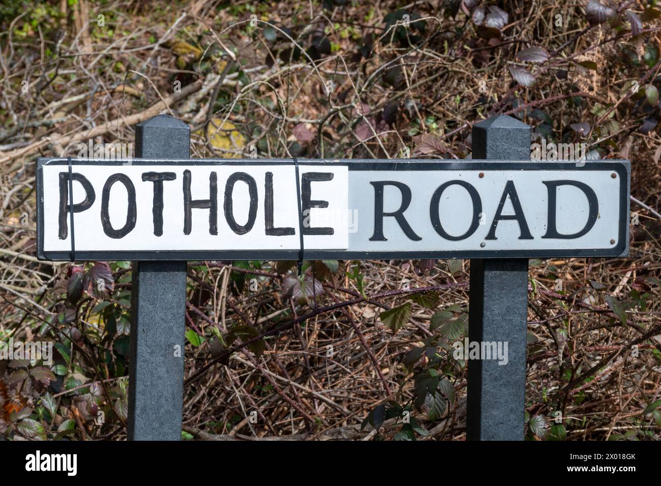 Pothole Road, panneau routier avec le nom réel de la rue remplacé par le mot Pothole probablement par le conducteur local frustré par les nids de poule non réparés, Royaume-Uni Banque D'Images