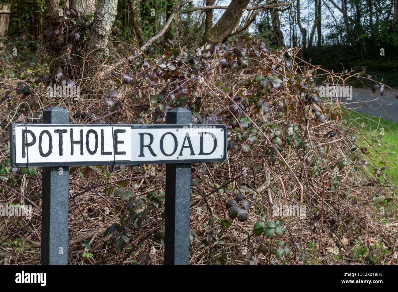 Pothole Road, panneau routier avec le nom réel de la rue remplacé par le mot Pothole probablement par le conducteur local frustré par les nids de poule non réparés, Royaume-Uni Banque D'Images
