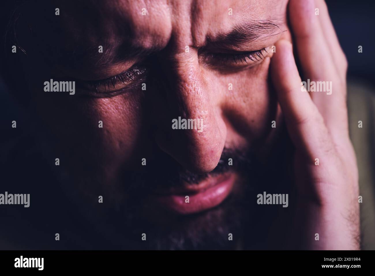 Désespoir et désespoir, gros plan du portrait d'un homme adulte pleurant triste en deuil dans une chambre sombre, mise au point sélective Banque D'Images