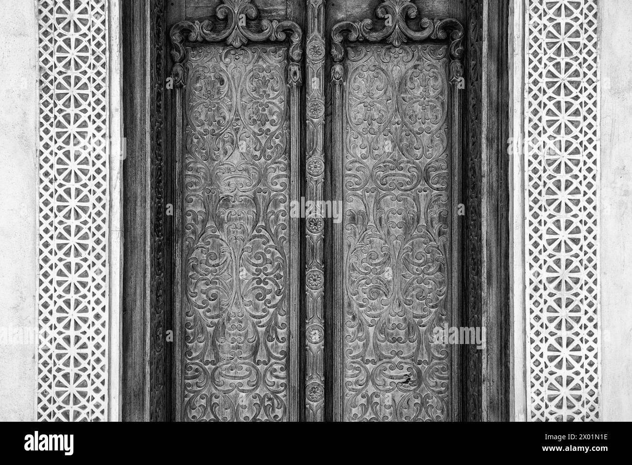 Vue monochrome filtrée d'une porte extérieure soigneusement sculptée avec plâtre sculpté entourant une maison arabe traditionnelle restaurée. Banque D'Images