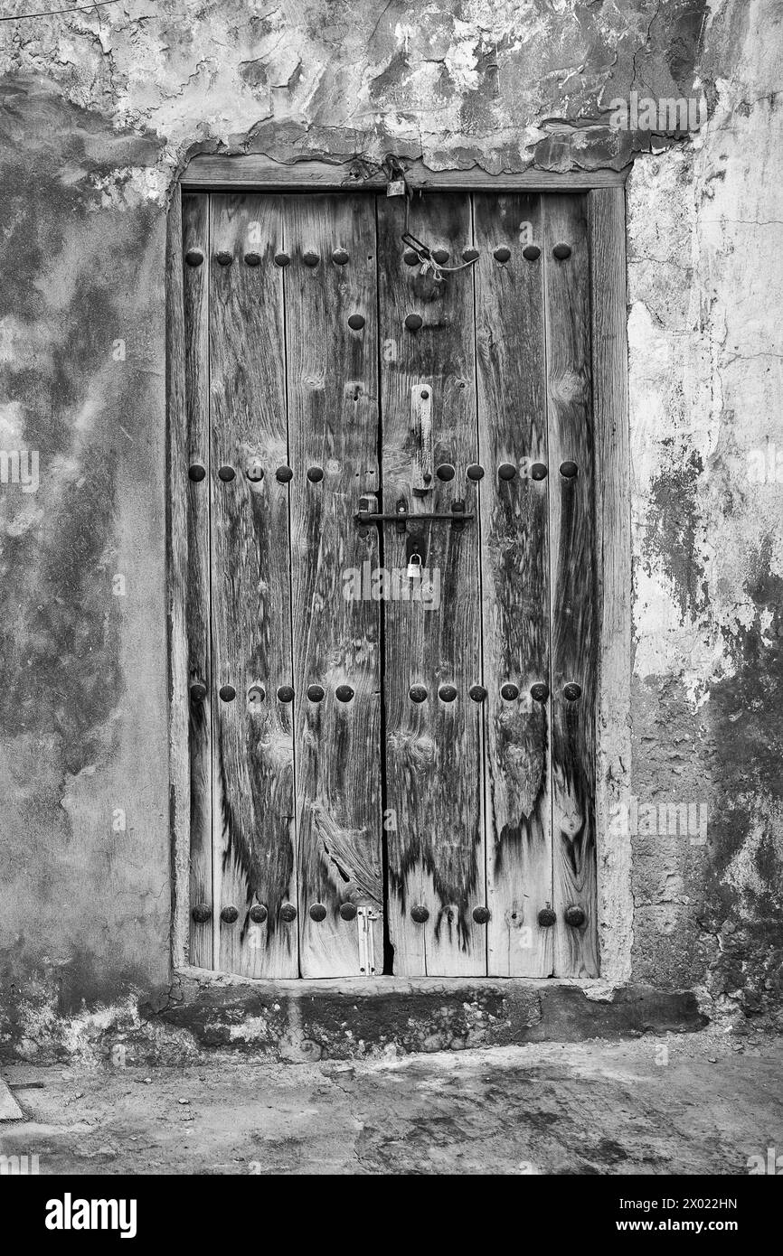 Image monochrome d'une porte abîmée et verrouillée donnant sur une maison arabe traditionnelle abandonnée et abandonnée. Banque D'Images