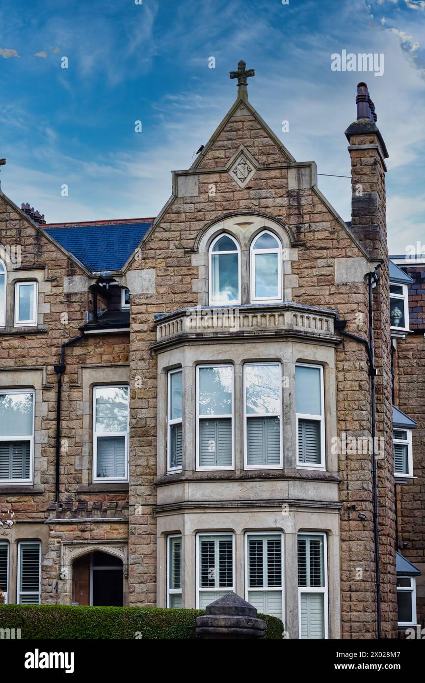 Bâtiment en pierre de style victorien avec un toit à pignons et des baies vitrées sous un ciel bleu avec des nuages, présentant des détails architecturaux classiques et un artisan Banque D'Images