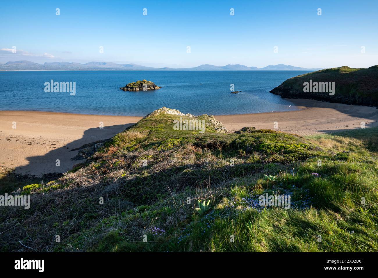 Belle vue depuis l'île de Llanddwyn sur Anglesey avec les montagnes du continent gallois à l'horizon. Banque D'Images
