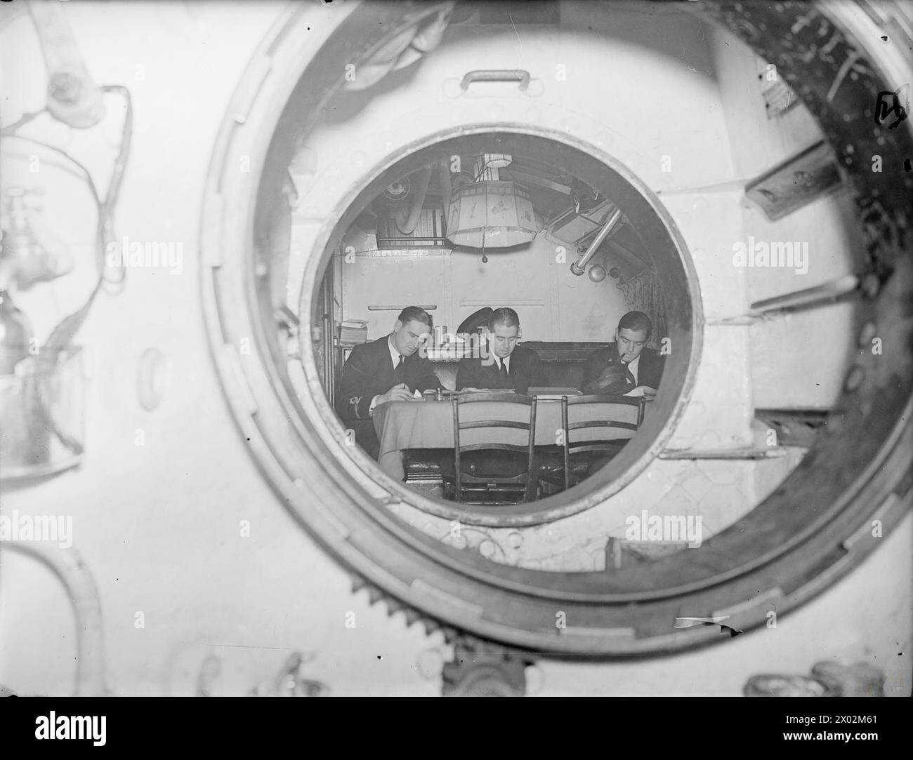 En septembre 1940, à bord du HM Submarine Snapper, des officiers sont montrés en train d'accomplir des tâches à travers une porte étanche ouverte. Banque D'Images