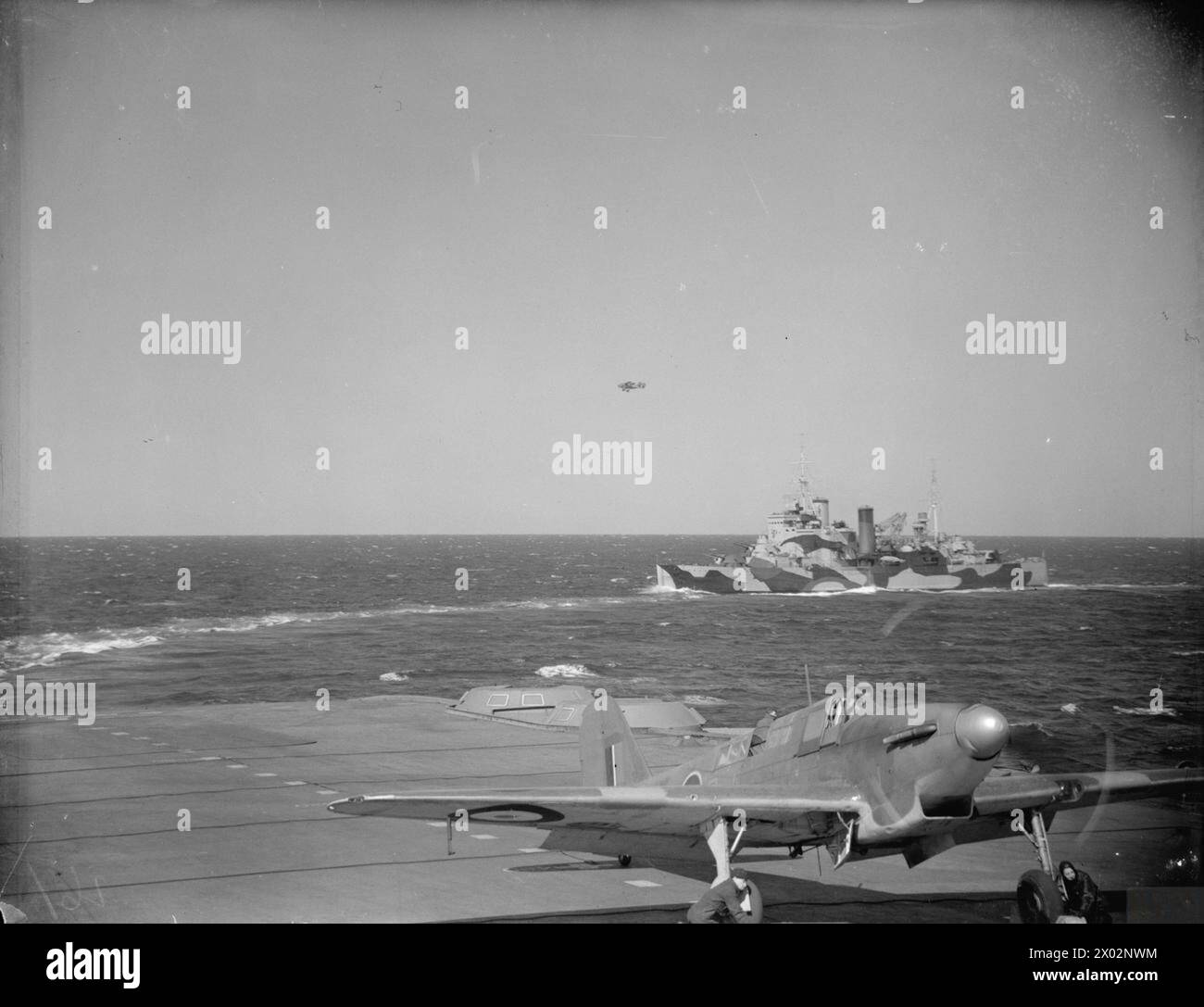 LES AVIONS ET NAVIRES DE GUERRE BRITANNIQUES ET AMÉRICAINS COUVRENT LE CONVOI RUSSE. MAI 1942, À BORD DU HMS VICTORIOUS EN MER ET À HVALFJORD, ISLANDE. - Un Fairey Fulmar sur le pont d'envol du HMS VICTORIOUS avec le croiseur HMS LONDON en arrière-plan Royal Navy, LONDRES (HMS), cuirassé Banque D'Images