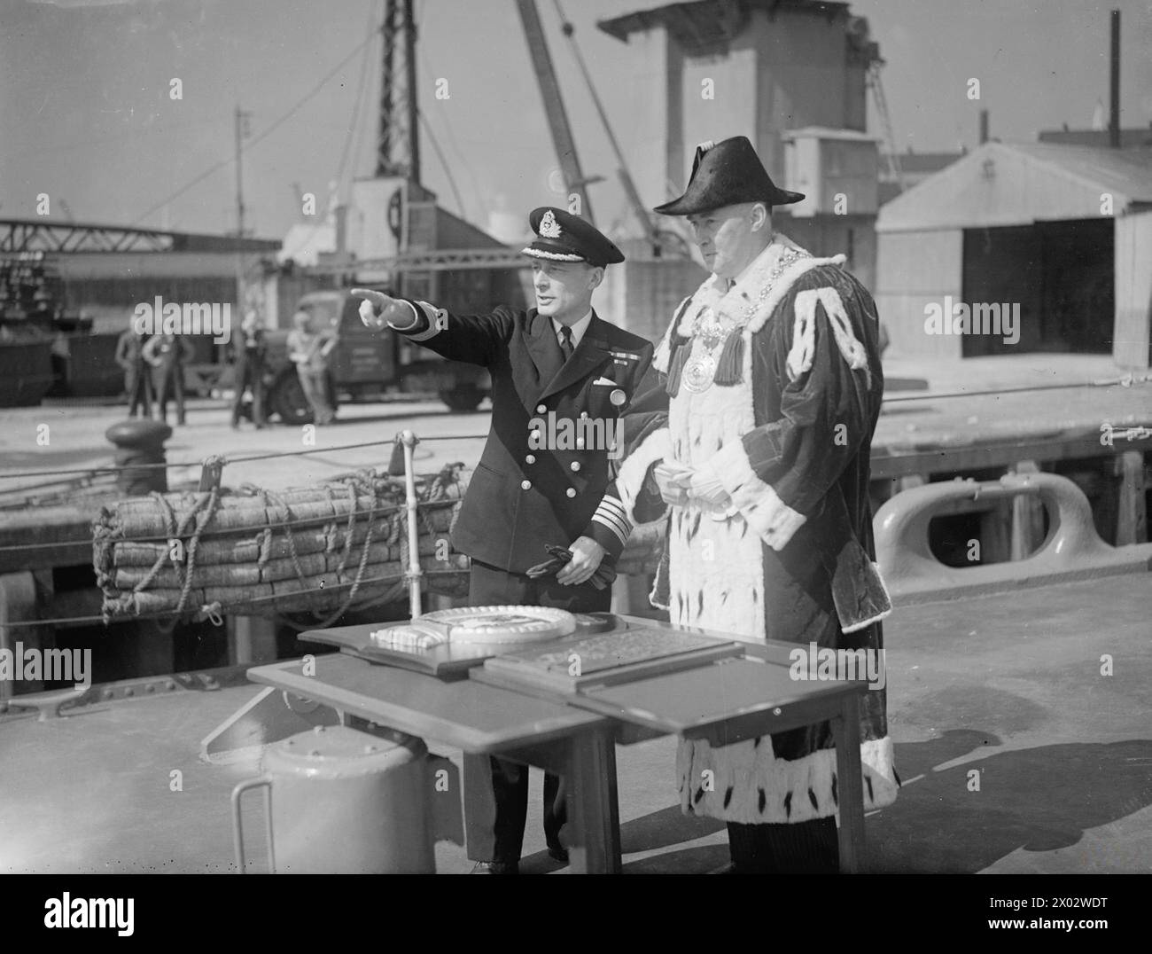 PLAQUE DE DUNDEE POUR LE CROISEUR CEYLON. 2 JUILLET 1943, GLASGOW. LE LORD PROVOST DE DUNDEE, LORD PROVOST GARNET WILSON, ACCOMPAGNÉ DE BAILIE COLIN BAIRD, BAILIE CALDWELL ET D'AUTRES MEMBRES DE LA CORPORATION ONT PRÉSENTÉ UNE PLAQUE AU CROISEUR BRITANNIQUE HMS CEYLON POUR COMMÉMORER SON ADOPTION PAR LES CITOYENS DE DUNDEE. LE CAPITAINE DU CEYLAN A FAIT UNE PRÉSENTATION DE RETOUR AUX CITOYENS ; UNE RÉPLIQUE DE LA CRÊTE DU CEYLAN, QUI A ÉTÉ REMISE AU NOM DES LORDS COMMISSAIRES DE L'AMIRAUTÉ. - Le Lord Provost et le Capitaine Amery-Parkes avec les deux plaques avant la présentation cere Banque D'Images