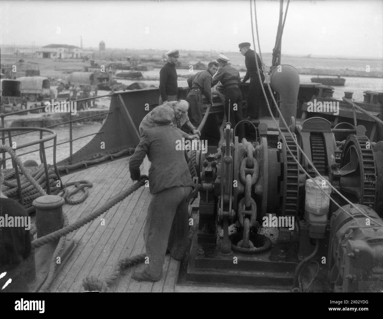 DE 'ALEX' À BENGHAZI : LES HOMMES DE LA MARINE MARCHANDE REVIENNENT AUX VICTOIRES DE LA 8E ARMÉE. DU 31 DÉCEMBRE 1942 AU 6 JANVIER 1943, ALEXANDRIE À BENGHAZI. LES HOMMES ET LES NAVIRES DE LA MARINE MARCHANDE SOUTENANT LA 8E AVANCÉE VICTORIEUSE DE L'ARMÉE EN AFRIQUE DU NORD. ILS TRANSPORTENT DES FOURNITURES VITALES D'ALEXANDRIE À BENGHAZI, OÙ LA ROYAL NAVY ET L'ARMÉE COOPÈRENT POUR DÉBARQUER LES MAGASINS ET LES ENVOYER AUX HOMMES DANS LA LIGNE DE COMBAT. - Arrivée sûre d'un marchand à Benghazi : quelques-unes des mains sur la tête fo'c'sle faire vite que le navire vient à côté Banque D'Images