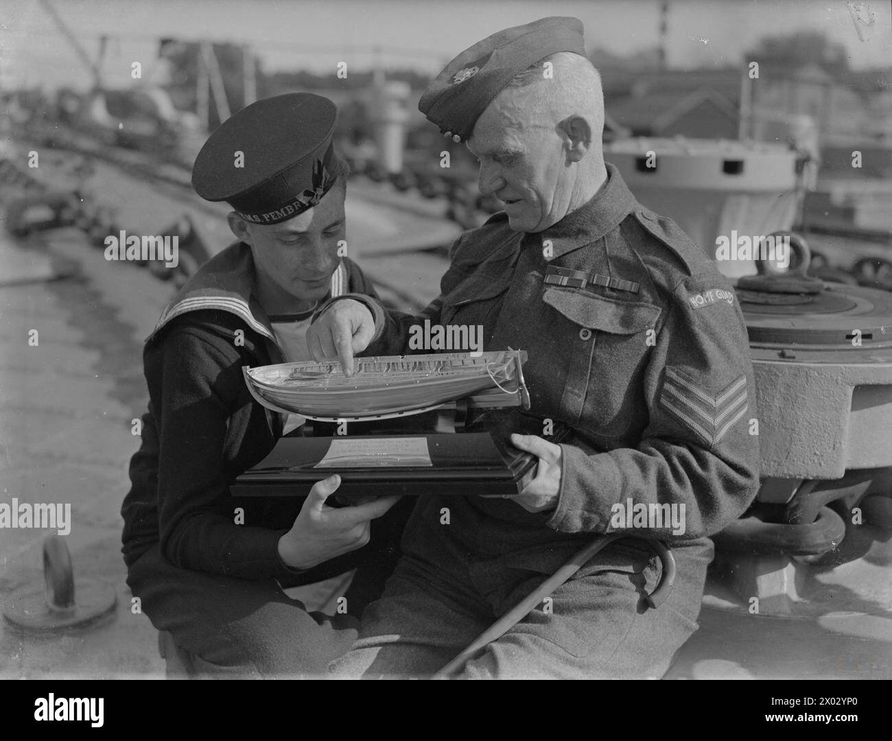 En 1941, à bord du HMS Euryalus, la liaison entre le croiseur et le Lancashire Fusiliers, forgée pour la première fois à Gallipoli en 1915, a été renouvelée. Lors d'une cérémonie, les Fusiliers ont remis au navire une cloche et un modèle argenté commémorant le sergent Dick Richards VC et son rôle à W Beach. Richards raconta le débarquement à un jeune marin. Banque D'Images