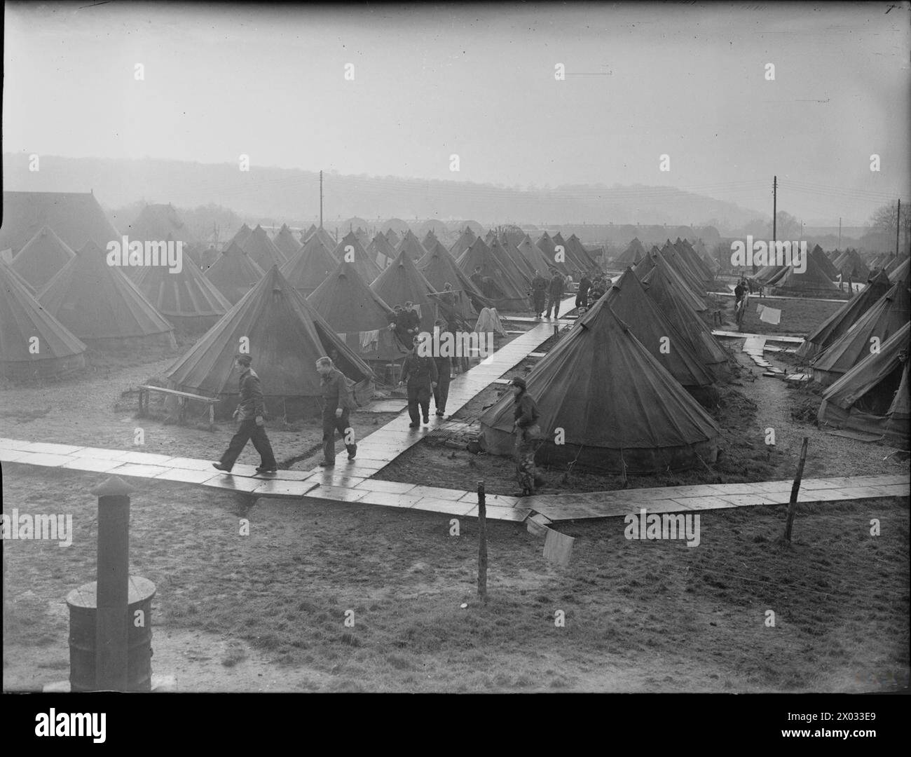 En 1945, des prisonniers de guerre allemands en Grande-Bretagne sont montrés marchant entre les tentes d'un camp de prisonniers de guerre, avec des huttes Nissen visibles en arrière-plan. Banque D'Images