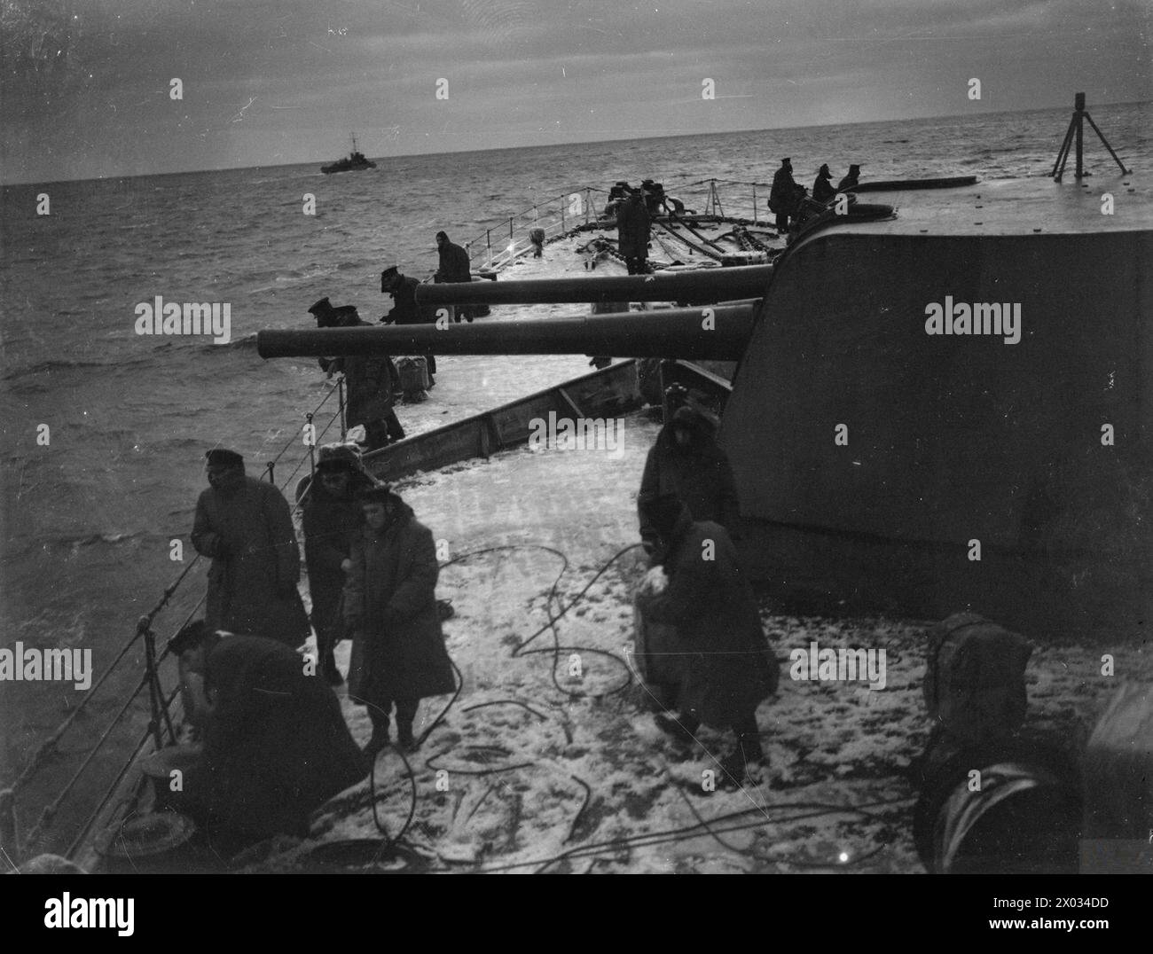 CONVOI EN RUSSIE, AVEC ESCORTE DE CROISEUR BRITANNIQUE SUR LA LIGNE DE VIE ARCTIQUE. DÉCEMBRE 1941, À BORD DU CROISEUR HMS SHEFFIELD. - Scène occupée sur la neige couverte fo`c'sle que les mains se préparent à `sortir des paravanes' à l'approche de la côte russe Banque D'Images