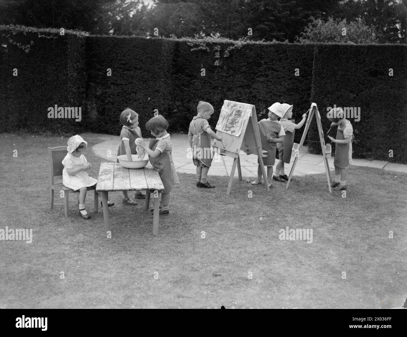 Les enfants s'adonnent à la peinture sur des chevalets et jouent avec des poupées dans les jardins de Montclair Nursery en Grande-Bretagne en 1942, reflétant la vie quotidienne et les activités récréatives de la crèche. Banque D'Images
