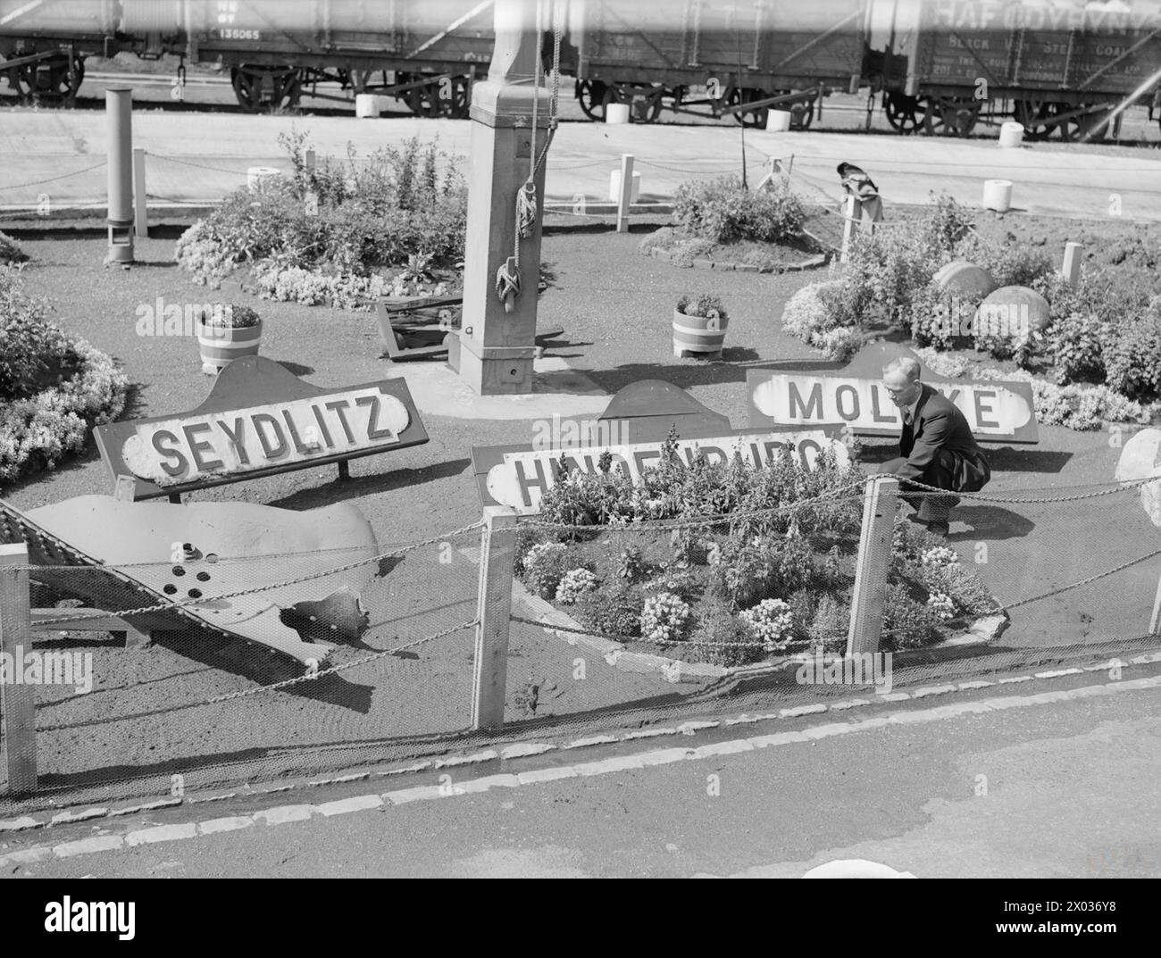 À ROSYTH ROYAL NAVAL DOCKYARD, LE 11 AOÛT 1944. - Les plaques nominatives des navires de guerre allemands de la dernière guerre qui décorent le petit jardin de fleurs devant le bureau du surintendant de l'amiral. Le chef Messenger J Henderson, qui travaille au chantier naval depuis 1919, s'occupe du jardin. Il a perdu son bras lors de la dernière guerre Banque D'Images