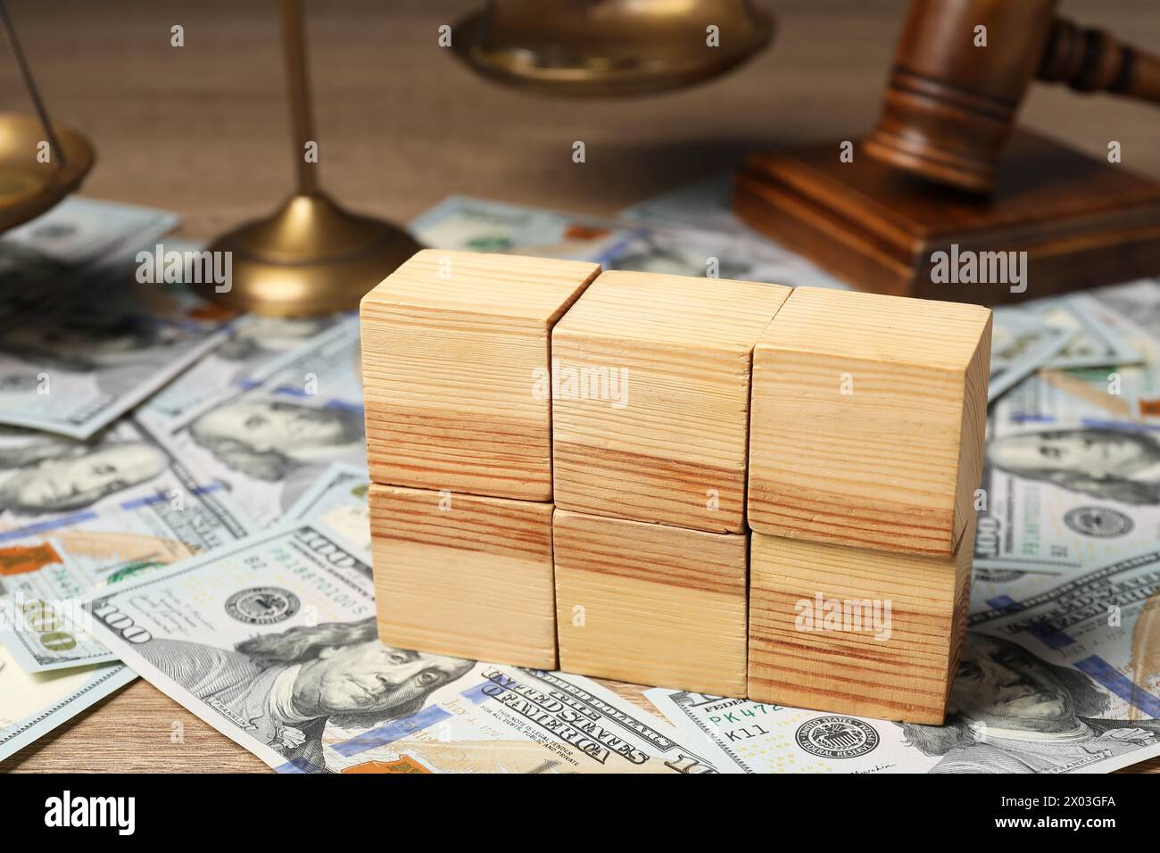 Droit fiscal. Cubes en bois vierges, billets de banque dollar, marteau et balances sur table, gros plan Banque D'Images