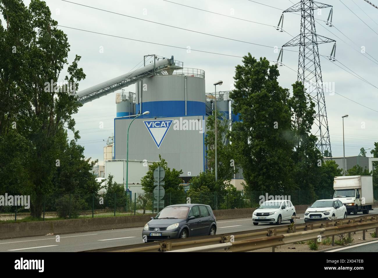 Lyon, France - 16 mai 2023 : un silo de ciment Vicat s'élève à côté d'une autoroute animée avec circulation sous un ciel nuageux. Banque D'Images