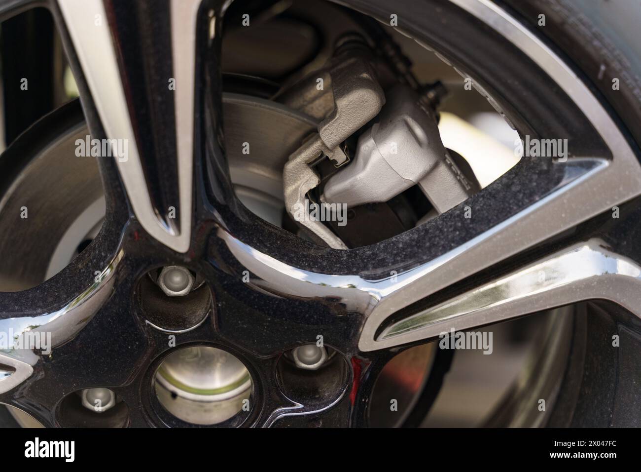 Une vue détaillée d'une roue de voiture montrant une plaquette de frein à proximité immédiate, mettant en évidence les composants mécaniques du système de freinage. Banque D'Images