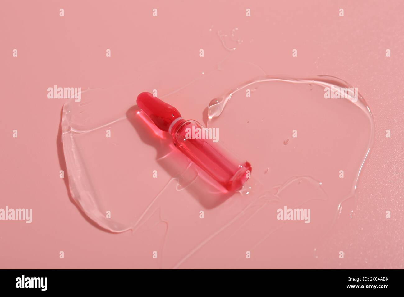 Ampoule de soin de la peau sur surface rose avec gel Banque D'Images