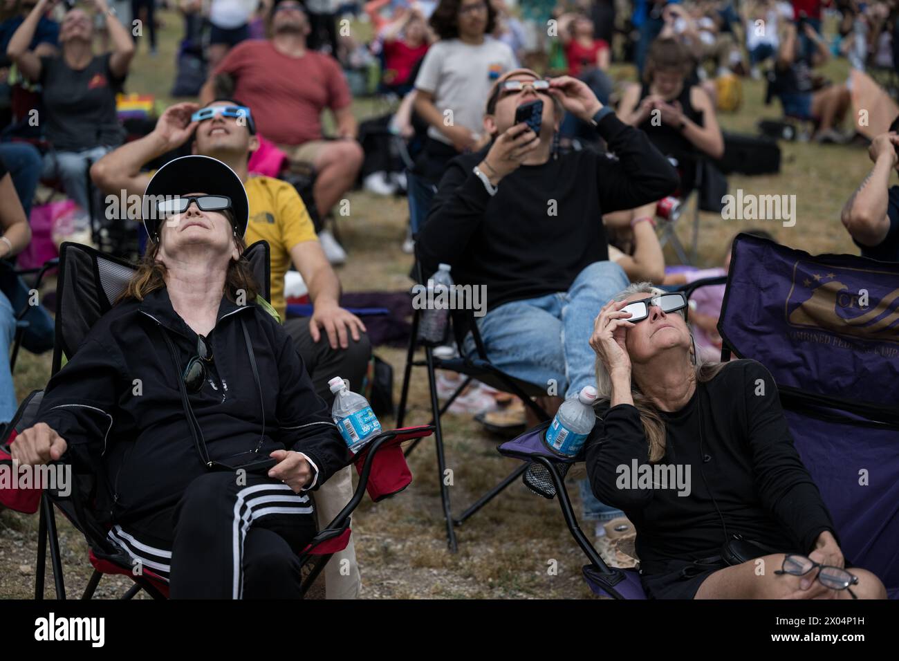 Kerrville (États-Unis d'Amérique). 08 avril 2024. Kerrville (États-Unis d'Amérique). 08 avril 2024. Les spectateurs portant des lunettes de protection regardent vers le haut alors que la lune couvre l'avant du Soleil lors de la fête d'observation d'une éclipse solaire, le 8 avril 2024, à Kerrville, Texas. Une éclipse solaire totale a balayé une partie étroite du continent nord-américain, du Mexique à la côte atlantique de Terre-Neuve, au Canada. Crédit : Aubrey Gemignani/NASA/Alamy Live News Banque D'Images