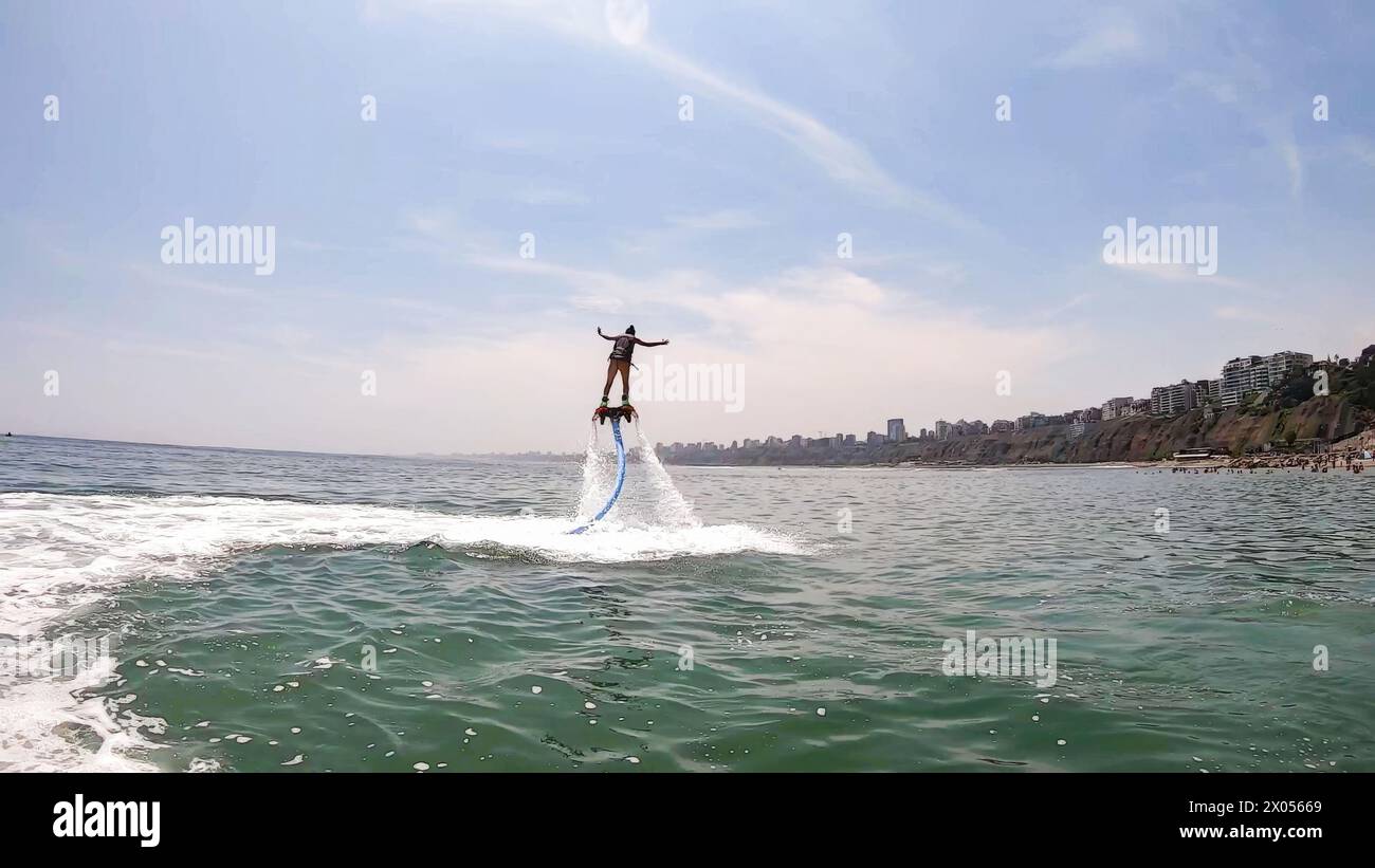 Scène exaltante d'une personne utilisant un jet-pack propulsé par l'eau sur une journée ensoleillée au bord de la plage Banque D'Images