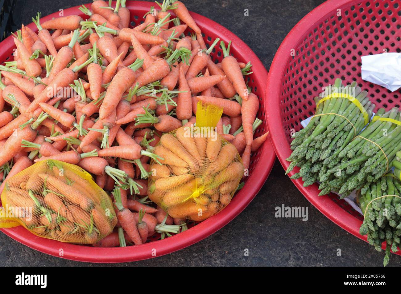 Paniers en plastique de carottes et asperges, produits agricoles de climat frais, Cho Da Lat (marché Dalat), Centre Vietnam Banque D'Images