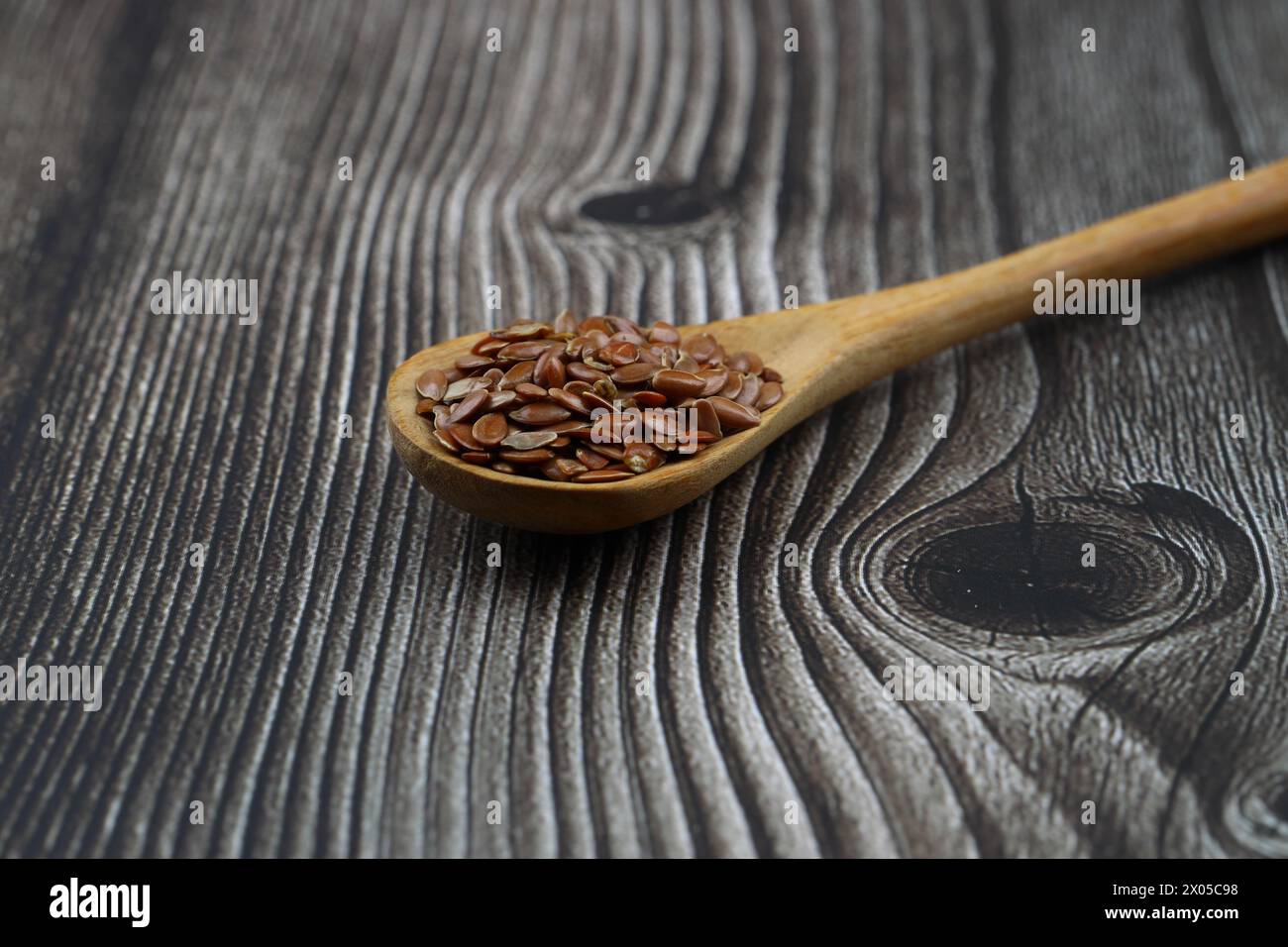 Graines de lin. Poudre de lin dans une cuillère en bois. Se tenir sur un fond en bois. Banque D'Images