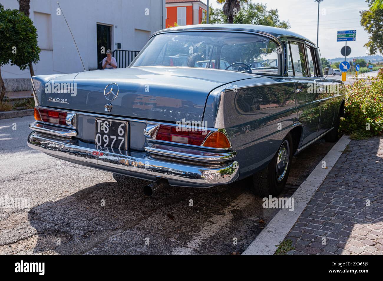 Une vieille voiture Mercedes vintage parfaitement restaurée est garée dans la rue par une journée d'été ensoleillée. Vieille Mercedes bleue sur une rue fleurie. Banque D'Images