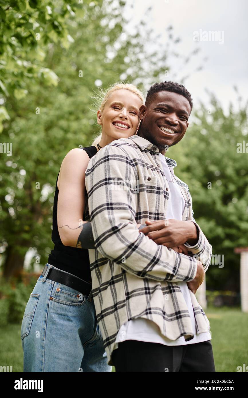 Un homme afro-américain et une femme caucasienne se tiennent ensemble dans l'herbe, se connectant avec la nature et les uns avec les autres. Banque D'Images
