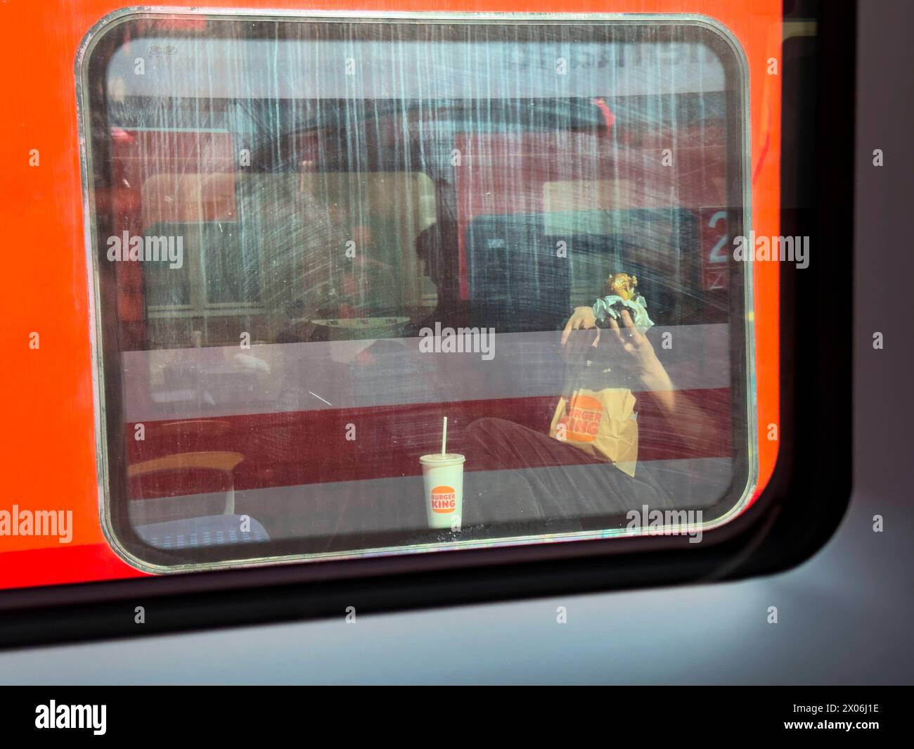 Une voyageuse mange de la restauration rapide de Burger King dans le train à la gare de Buchloe le 27 mars 2024 à Augsbourg, en Allemagne Banque D'Images