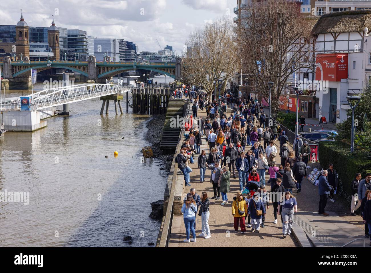 People on Queen's Walk passe devant le Shakespear's Globe Theatre sur la rive sud de la Tamise près de l'embarcadère Bankside, Southwark, Londres Banque D'Images